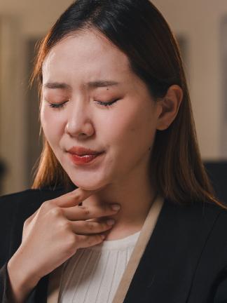 Woman suffering from sore throat is holding her throat