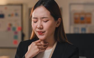 Woman is holding her throat in discomfort due to sore throat