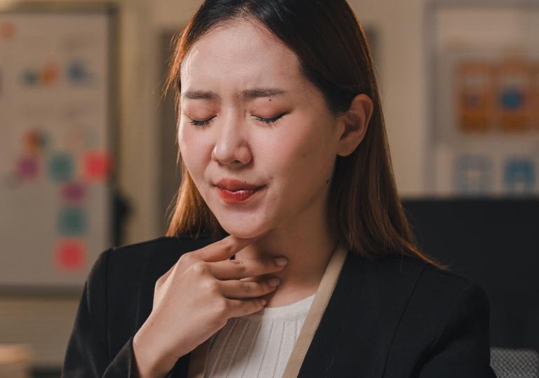 Woman  holding her throat, obviously suffering from sore throat