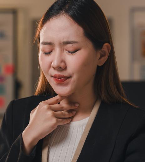 Woman suffering from sore throat holds her throat