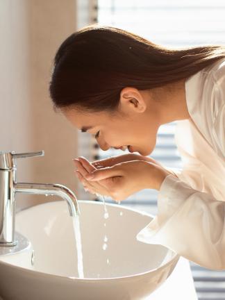 girl in bathroom, washing her face with water
