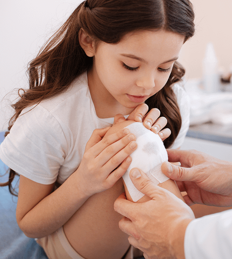 little girl treating wound covered in gauze