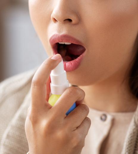 Woman with her mouth open, about to spray BETADINE Throat Spray